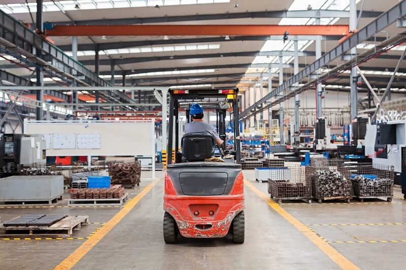 worker driving forklift in factory