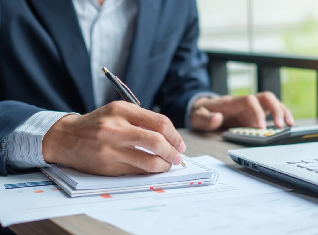 Businessman writing on tablet and using a calculator; representing tax planning