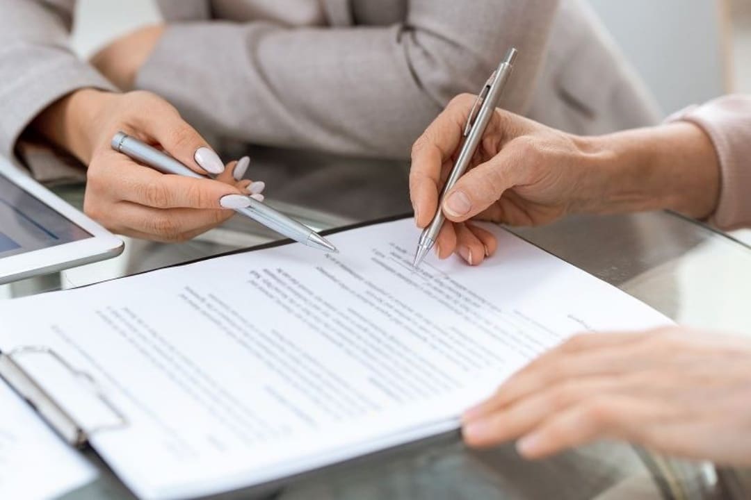 2 people reviewing and signing paperwork, representing a buy sell agreement